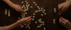 two people are playing with wooden letters on a table together and one person is placing them in the middle