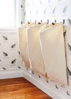 three laundry bags hanging on the wall in front of a window with black and white dog wallpaper