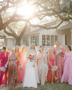 a group of women standing next to each other in front of a tree and house