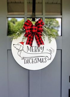 a christmas door hanger with a red bow hanging from it's front door