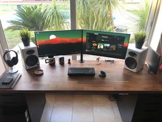 two computer monitors sitting on top of a wooden desk next to a keyboard and mouse