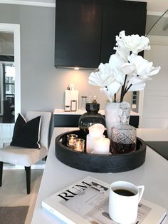 a tray with flowers and candles on top of a table in a living room next to a chair