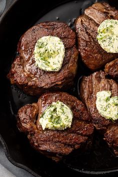 four steaks in a cast iron skillet with cream cheese on top