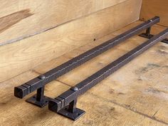 two metal bars sitting on top of a wooden floor next to a wall with wood planks