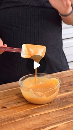 a person pouring cheese into a bowl on top of a wooden table