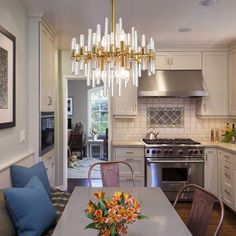 a chandelier hanging from the ceiling in a kitchen next to a table with chairs