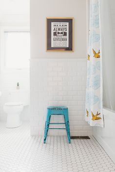 a bathroom with a blue step stool in front of a white tiled wall and floor