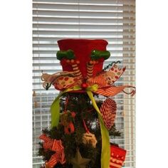 a decorated christmas tree in front of a window with the top hat on it's head