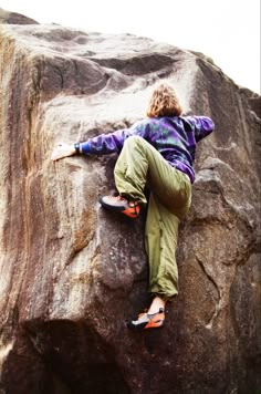 a person climbing up the side of a large rock