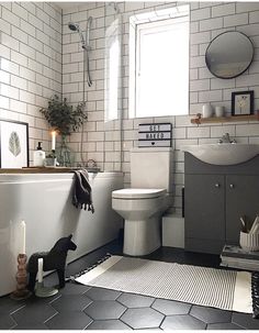 a bathroom with black and white tile flooring, a bathtub, toilet and sink