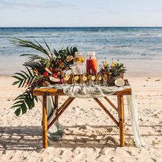 a table set up on the beach with drinks