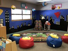 an office decorated in blue and red with bean bags on the floor, children's play area