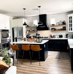 a kitchen with black and white cabinets, wood floors, and an island in the middle