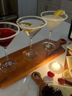 three martinis sitting on top of a wooden cutting board