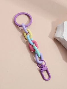 a pair of scissors and a chain on a pink surface next to a roll of toilet paper