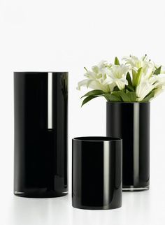 three black vases with white flowers in them