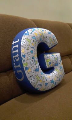 an inflatable letter sitting on top of a brown couch next to a wall