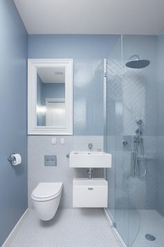 a white toilet sitting next to a walk in shower under a bathroom mirror above a sink