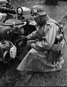 a man sitting on the ground next to an old motorcycle with a helmet and goggles