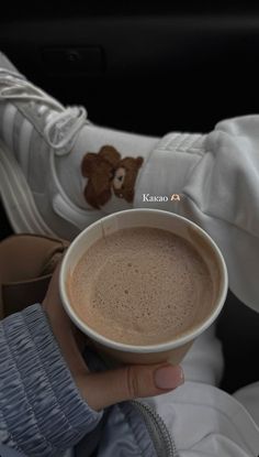 a person holding a cup of coffee in their hand with a teddy bear on it