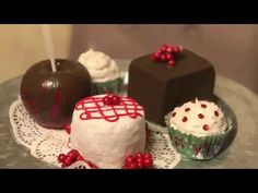 three cakes and two cupcakes sitting on a doily with red bow ties