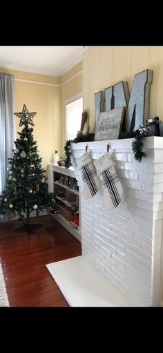 a fireplace with stockings hanging from it's mantle and christmas tree in the background