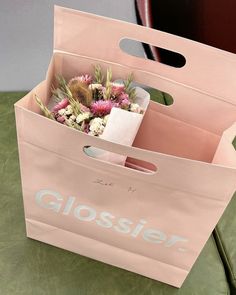 a pink shopping bag with flowers in it