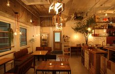 the interior of a restaurant with wooden tables and chairs, lights hanging from the ceiling