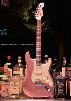 a pink guitar sitting on top of a counter next to bottles and liquor bottle openers