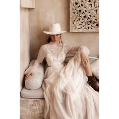 a woman in a white dress and cowboy hat sitting on a bench