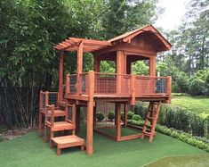 a wooden play structure with stairs and steps in the grass next to a fenced area