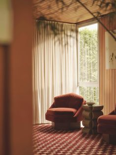 two red chairs sitting in front of a window