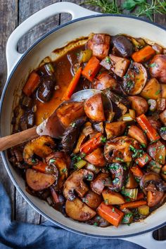 a pot filled with stew and vegetables on top of a wooden table