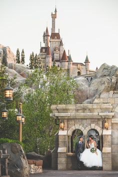 a bride and groom standing in front of a castle at disney's animal kingdom