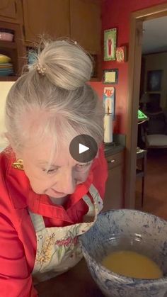 an older woman holding a bowl with liquid in it and looking down at the ground