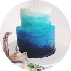 a blue and white cake sitting on top of a table next to a teapot