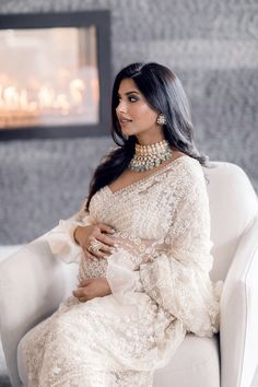 a woman in a white dress sitting on a chair