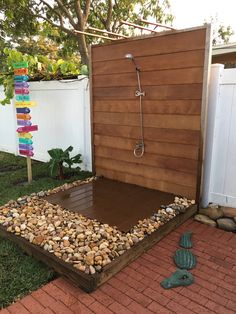 an outdoor shower in the middle of a yard with rocks and gravel on the ground