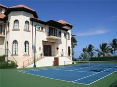 a tennis court in front of a large house