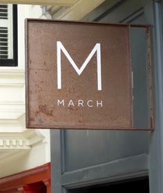 a sign hanging from the side of a building that says march in front of it