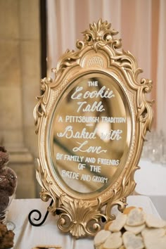 a gold framed mirror sitting on top of a table next to cookies and candies