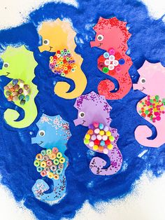 seahorses made out of buttons and beads are on the blue paper with white background