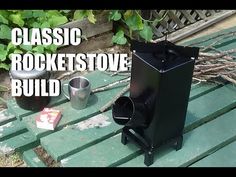 a black stove sitting on top of a wooden table next to a cup and plant