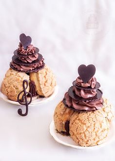 two desserts with chocolate frosting and hearts on top are sitting on white plates