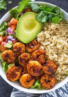 a bowl filled with shrimp and rice next to an avocado on the side