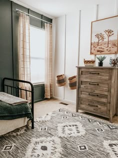 a bedroom with a bed, dresser and rug on the floor in front of a window