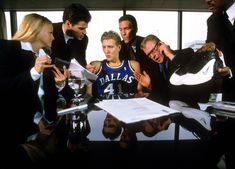 a group of men and women standing around a table with papers in front of them