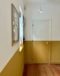 the hallway is painted yellow and white with wood flooring on either side of the door