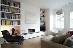 a living room filled with furniture and bookshelves next to a fire place in the wall