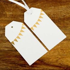 two white tags with an orange and white design are on a wooden surface, one has a string attached to it